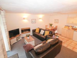 a living room with a leather couch and a television at Bluebell Cottage in Paignton
