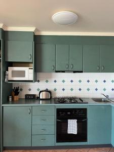 a kitchen with green cabinets and a stove top oven at Vista Di Mare in Lorne