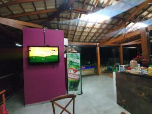 a room with a purple wall with a television and a refrigerator at CHÁCARA Na Represa in Ibiúna +3 photos