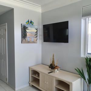 a living room with a tv on a white wall at Ocean Breeze Villa 242 in Nassau