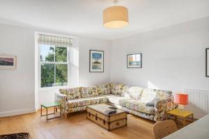 a living room with a couch and a table at Manacles - Spacious flat near beach with sea views & parking in Falmouth