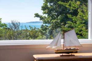 a toy boat sitting on a table in front of a window at Manacles - Spacious flat near beach with sea views & parking in Falmouth