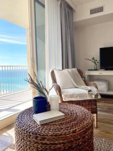 a living room with a wicker chair and a table with a book at Shores of Panama Unit 1209 in Panama City Beach