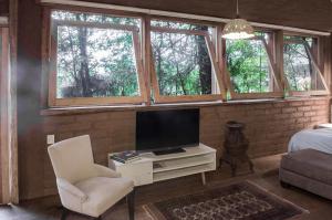 un soggiorno con TV, sedia e finestre di Lofts in The Forest a Avándaro