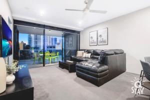a living room with a leather couch and a large window at KIDS STAY FREE in Hinterland View 1 Bedroom SPA Apartment at Circle on Cavill - Q STAY in Gold Coast