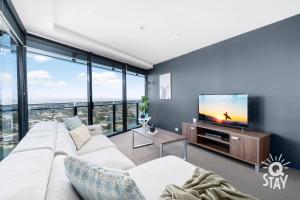 a living room with a white couch and a flat screen tv at KIDS STAY FREE in Hinterland View 1 Bedroom SPA Apartment at Circle on Cavill - Q STAY in Gold Coast