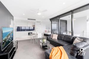 a living room with a black leather couch and a tv at KIDS STAY FREE in Hinterland View 1 Bedroom SPA Apartment at Circle on Cavill - Q STAY in Gold Coast