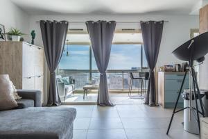 a living room with curtains and a view of a city at Admire Panoramic Ocean Views Through Walls of Windows in Cannes