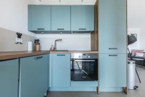 Una cocina con gabinetes azules y un fregadero. en LB Vacation Rentals I Admire Panoramic Ocean Views Through Walls of Windows, en Cannes