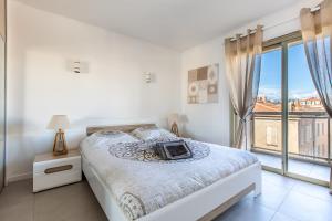 Un dormitorio blanco con una cama y una ventana grande. en LB Vacation Rentals I Admire Panoramic Ocean Views Through Walls of Windows, en Cannes