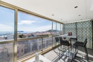a room with a balcony with a table and chairs at Admire Panoramic Ocean Views Through Walls of Windows in Cannes