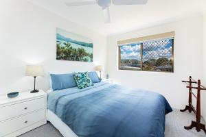 a white bedroom with a blue bed and a window at Braemar 3 in Forster