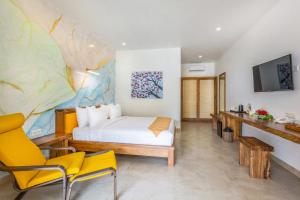 a hotel room with a bed and two chairs at Pearl Sunset Resort in Gili Trawangan