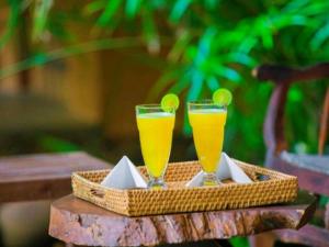 two glasses of orange juice sitting on a tray at River Side Cottage in Udawalawe