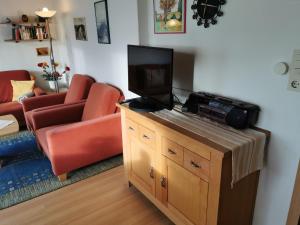 ein Wohnzimmer mit einem TV auf einem Holzschrank in der Unterkunft Haus Juist - Schillig in Wangerland
