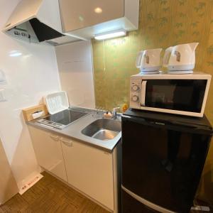 a small kitchen with a sink and a microwave at Guest House One More Heart at Kyoto Station South 6 in Nishi-kujō-Toriiguchichō