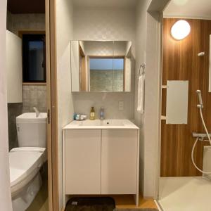 a bathroom with a sink and a toilet and a mirror at Guest House One More Heart at Kyoto Station South 6 in Nishi-kujō-Toriiguchichō