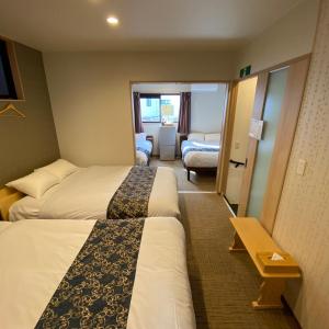 a hotel room with two beds and a living room at Guest House One More Heart at Kyoto Station South 6 in Nishi-kujō-Toriiguchichō