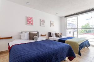 a bedroom with two beds and a large window at Condesa, Depto 2 recamaras. in Mexico City