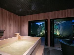 uma banheira de hidromassagem num quarto com portas de vidro deslizantes em Bettei Fujiya em Miyajima