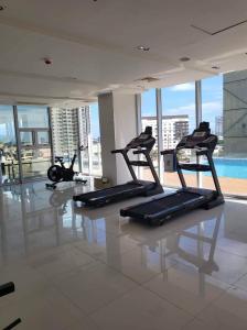 a gym with treadmills and a pool in a building at Hola! Condotel @ Inspiria Davao in Davao City