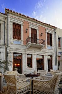 un edificio con sillas y una mesa frente a él en Civitas Suites Hotel, en Rethymno