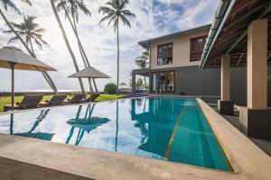 una piscina di fronte a una casa con palme di Kabalana House by Ceilao Villas ad Ahangama