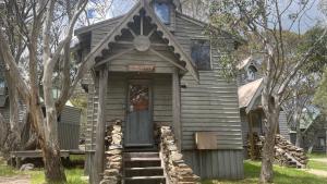 a small wooden house with a front door and trees at Alpine Retreat in Dinner Plain