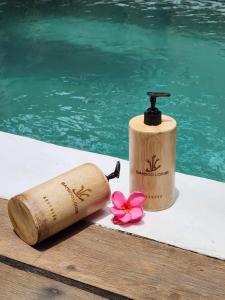 a wooden bat and bottle next to a swimming pool at Bamboo Lodge 2 in Gili Trawangan