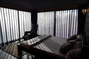 a bedroom with a bed and a large window with vertical blinds at Ngôi Làng Trong Tranh, Leading-Kiwuki Village in Bao Loc
