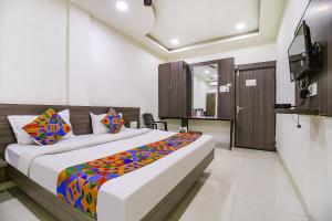 - une chambre avec un grand lit et une couverture colorée dans l'établissement FabExpress Aditya Regency-Near Railway Station-Bhopal, à Bhopal