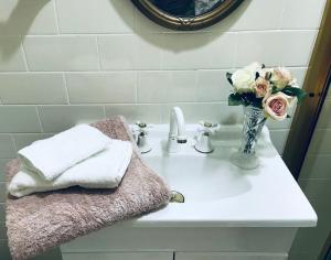 a bathroom sink with a vase of flowers on it at Hawk's Nest Bed & Breakfast in Bathurst +18 photos
