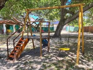 um parque infantil com um baloiço debaixo de uma árvore em Chalés Jardins dos Cajueiros em Tamandaré