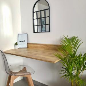 a mirror on a wall with a wooden table and a chair at Studio Kooka nui - Private apartment in Papeete