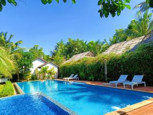 a swimming pool with two chairs and a house at La Casa Resort in Phú Quốc