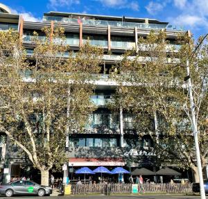 un bâtiment avec des tables et des parasols bleus devant lui dans l'établissement 108 Astral Apartments, à Melbourne