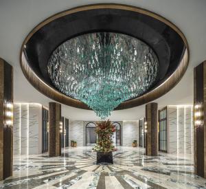 a large chandelier hangs from the ceiling of a lobby at Fili Hotel at Nustar Cebu in Cebu City
