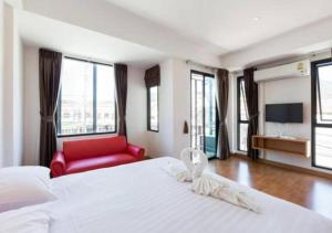 um quarto com uma grande cama branca e uma cadeira vermelha em Buk Inn Hotel SHA Plus em Praia de Kamala