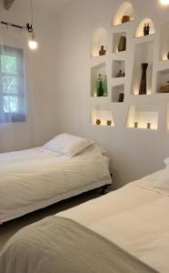 2 camas en una habitación con paredes blancas y estanterías en La Casa de la Huerta, en Tarija