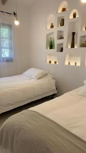 two beds in a room with white walls and shelves at La Casa de la Huerta in Tarija