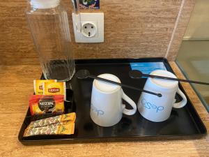 a tray with two coffee mugs and snacks on it at Desatu Hotel in Medan