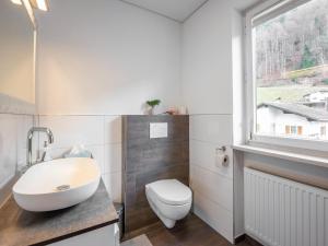 a bathroom with a toilet and a sink and a window at Ferienhaus Linde in Bartholomäberg