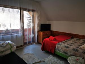 um quarto com uma cama com um cobertor vermelho e uma janela em Cabana "Trei Brazi " Retezat em Rîu de Mori