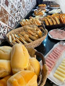 ein Buffet mit Brot und Gebäck auf dem Tisch in der Unterkunft Pousada Solari s in Rio das Ostras