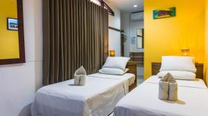 two beds in a room with yellow walls at Bulskamp Inn in El Nido