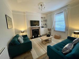 uma sala de estar com dois sofás verdes e uma lareira em Traditional Cottage in West Kilbride Village em Seamill