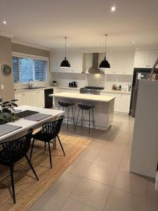 uma cozinha com armários brancos e uma mesa e cadeiras em Quiet family retreat getaway - Wildlife Park, Sovereign Hill, Kryall Castle and city at your door - modern apartment, 8 guests em Ballarat