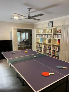 uma mesa de pingue-pongue num quarto com uma estante de livros em Quiet family retreat getaway - Wildlife Park, Sovereign Hill, Kryall Castle and city at your door - modern apartment, 8 guests em Ballarat