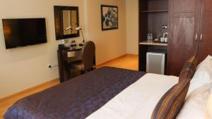 Schlafzimmer mit einem Bett, einem Schreibtisch und einem TV in der Unterkunft Strato Hotel By Warwick in Doha