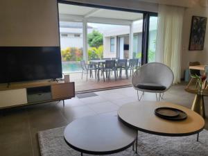 a living room with two tables and a flat screen tv at Villa de Luxe à Grand Baie avec piscine V12 in Grand Baie